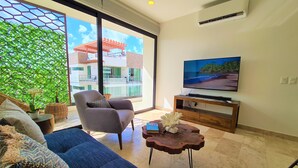 A modern living room with a sofa, a chair, a coffee table, and a TV on a wooden stand. - Bahay By Riviera Rentals (Playa del Carmen)