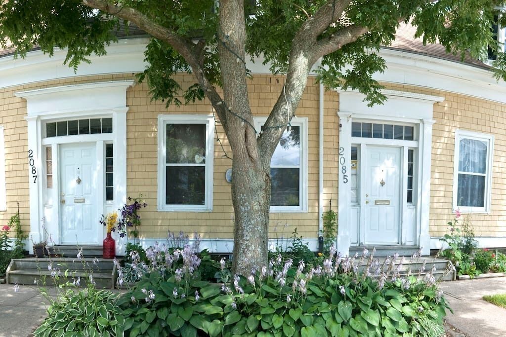 A two-story house with a front porch, numbered 2085, and a large tree in front.