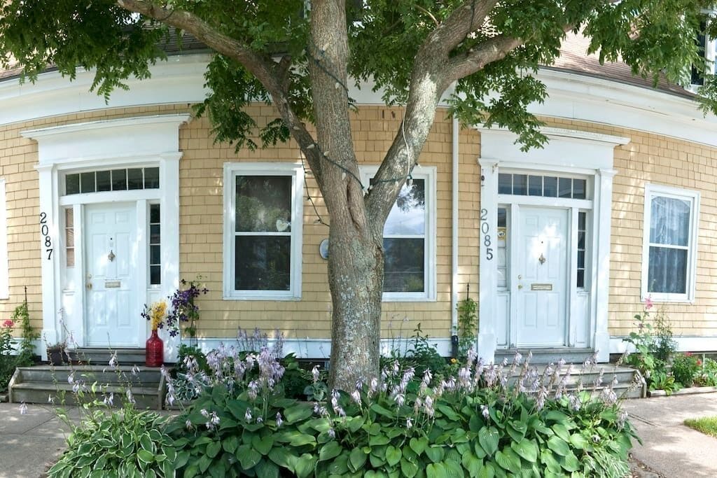 A two-story house with a front porch, numbered 2085, and a large tree in front.