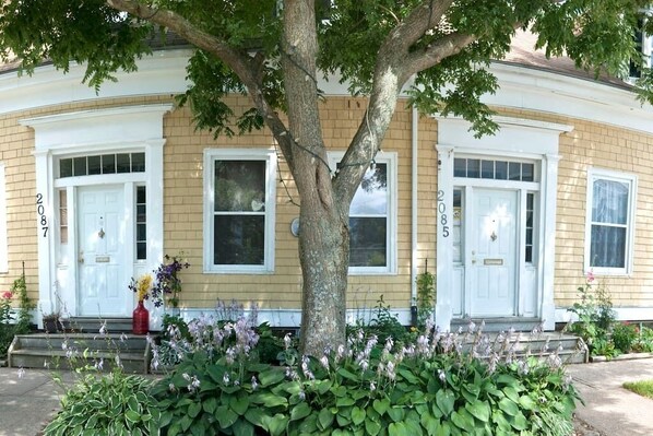A two-story house with a front porch, numbered 2085, and a large tree in front.