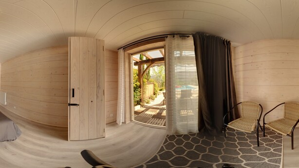Una habitación con techo curvo, una cama, una silla y vistas a un área exterior con piscina.