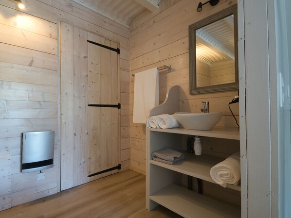 Une salle de bain en bois avec un lavabo intégré, un porte-serviettes et un miroir.