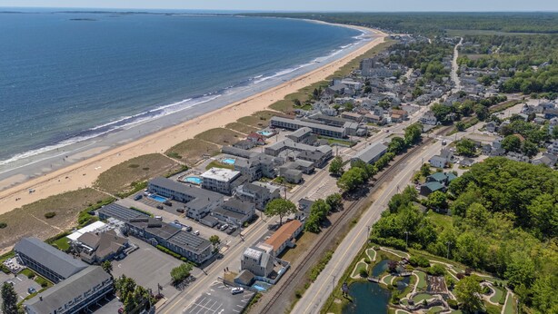 An aerial view of a coastal town with a beach, residential buildings, and a small lake. - Sands Townhouses (Old Orchard Beach)