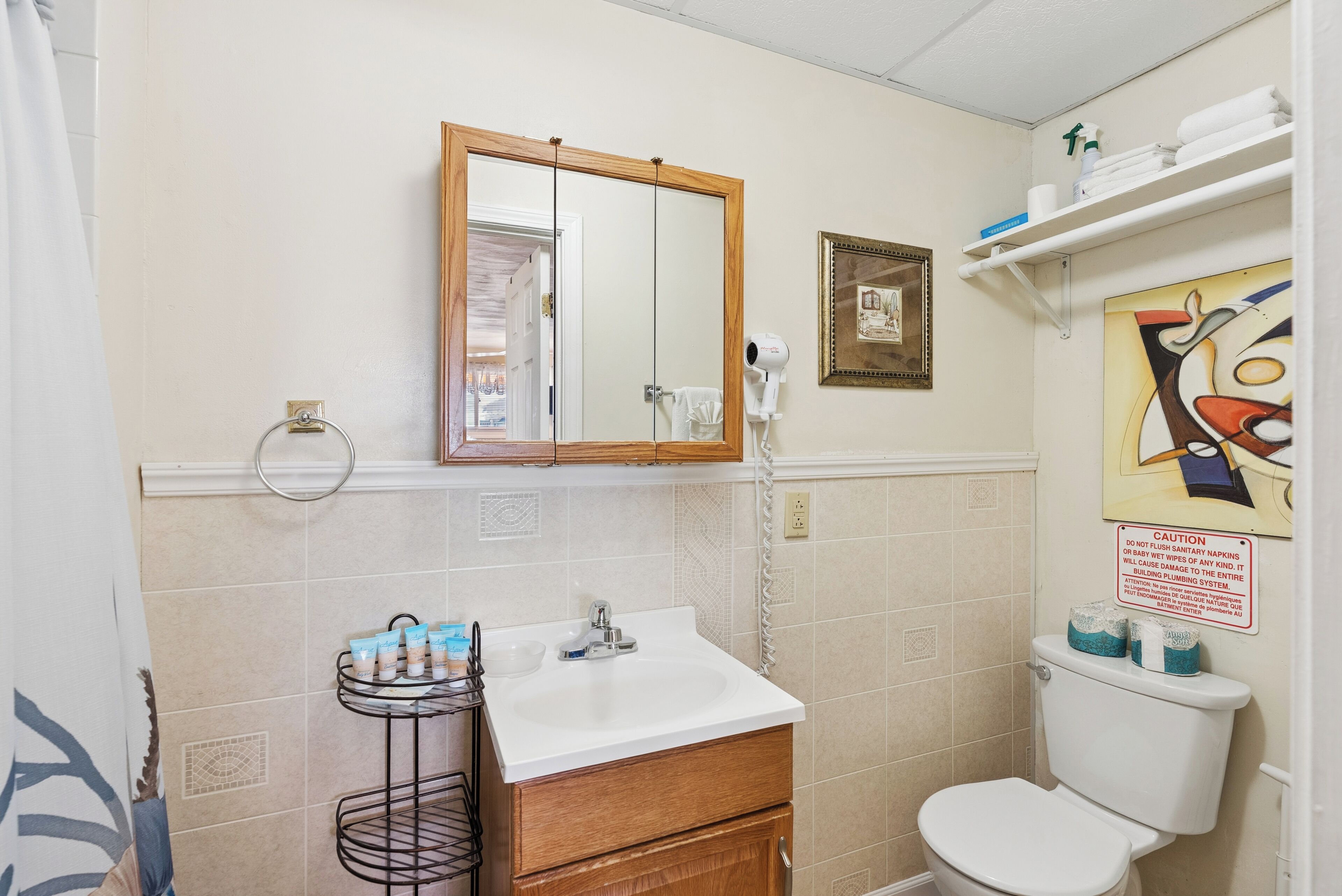Une salle de bain équipée d’un lavabo, d’un miroir, de toilettes et d’un porte-serviettes.