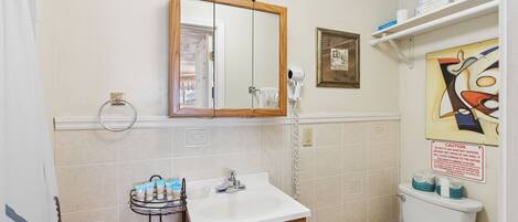 Une salle de bain équipée d’un lavabo, d’un miroir, de toilettes et d’un porte-serviettes.