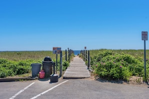 Un muelle de madera que conduce a la playa con un cartel que dice 'NO ESTACIONAR EN NINGÚN MOMENTO'.