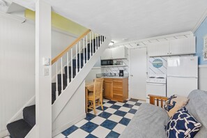 Een compacte keuken met een eethoek, een trap en een woonruimte met een geruite vloer.