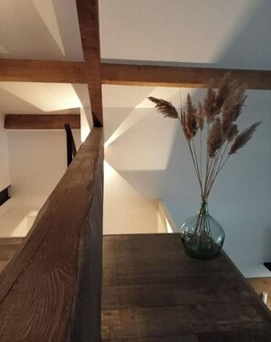 A simple staircase with a vase of pampas grass on a table below.
