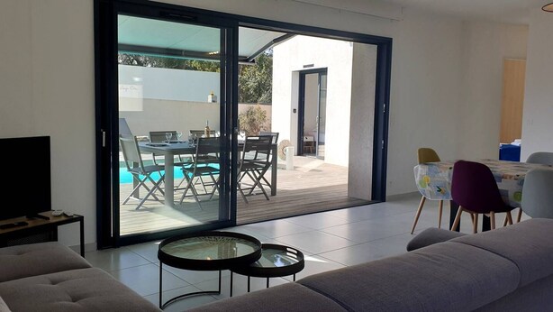 A modern living room with a sofa, a coffee table, and a dining area with a table and chairs. - Villa Rossa, 6 pers dans résidence avec piscine chauffée privée (Lecci)