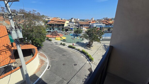 A residential area with a curved road, a playground, and buildings with red-tiled roofs. - Recanto Del Mare (Arraial do Cabo)