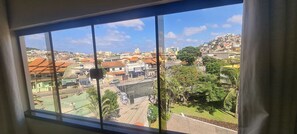 A view from a window overlooking a residential area with houses, a street, and a sports field. - Recanto Del Mare (Arraial do Cabo)