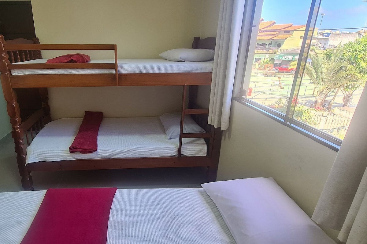 A bunk bed with a desk and chair, a window with a view of the outside, and a curtain on the window.