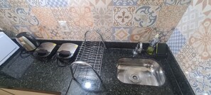 A kitchen with a sink, a coffee machine, a kettle, and a bottle of dish soap. - Recanto Del Mare (Arraial do Cabo)