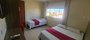 Una habitación de hotel con dos camas, televisión, ventana con vista a la ciudad y una puerta.