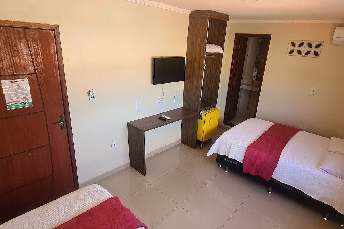 Ein Schlafzimmer mit Bett, Schreibtisch, Fernseher und Klimaanlage.