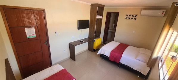 Un dormitorio con cama, escritorio, televisor y aire acondicionado.