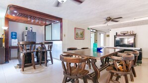 Un comedor con una mesa y sillas de madera, un refrigerador y un dispensador de agua.