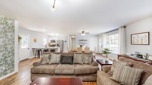 Un salon spacieux avec un grand canapé, un coin repas et une cuisine à l’arrière-plan.
