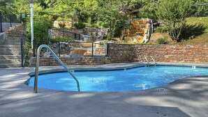 En swimmingpool med en mur av sten och metallräcken.