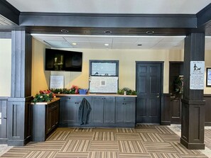 A reception area with a counter, a wall-mounted TV, and a sign indicating pet policy. - Apex Mountain ~ Hillside Hideout ~ Apex Mountain Inn (Apex Mountain Resort)