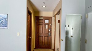 A hallway with a wooden door at the end, a light switch, and a framed picture on the wall. - Apex Mountain ~ Hillside Hideout ~ Apex Mountain Inn (Apex Mountain Resort)