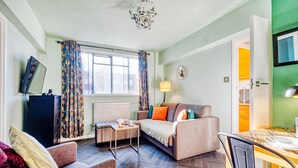 A living room with a sofa, armchair, and a small table with a lamp. - Hardwood Home  - One Bedroom Apartment, Sleeps 2 (London)