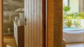 A wooden interior with a stone wall, a wooden door, and a view of an outdoor balcony.