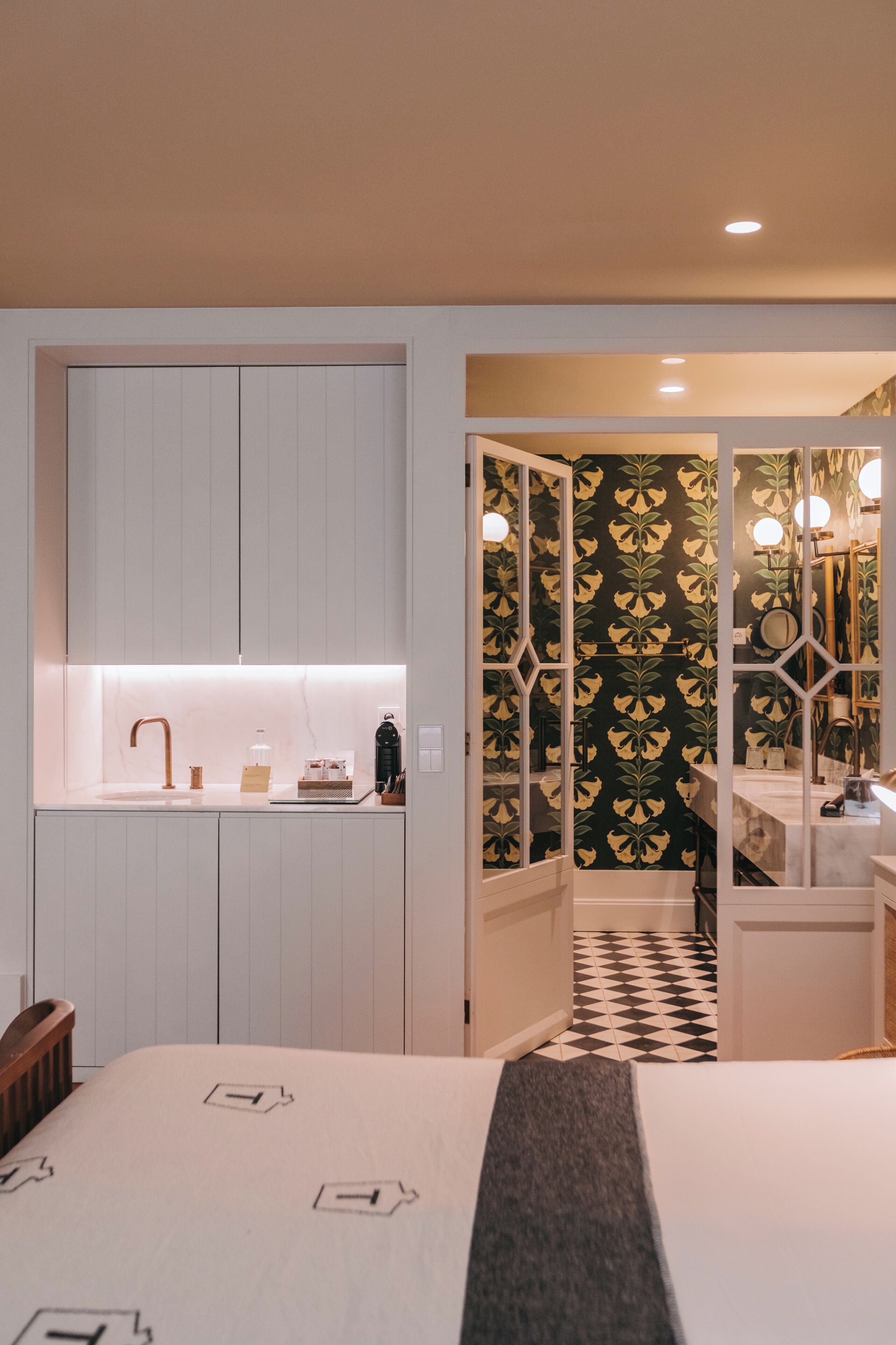 Une chambre à coucher comprenant un lit, une table de chevet, une commode et une salle de bain avec un miroir et un lavabo.