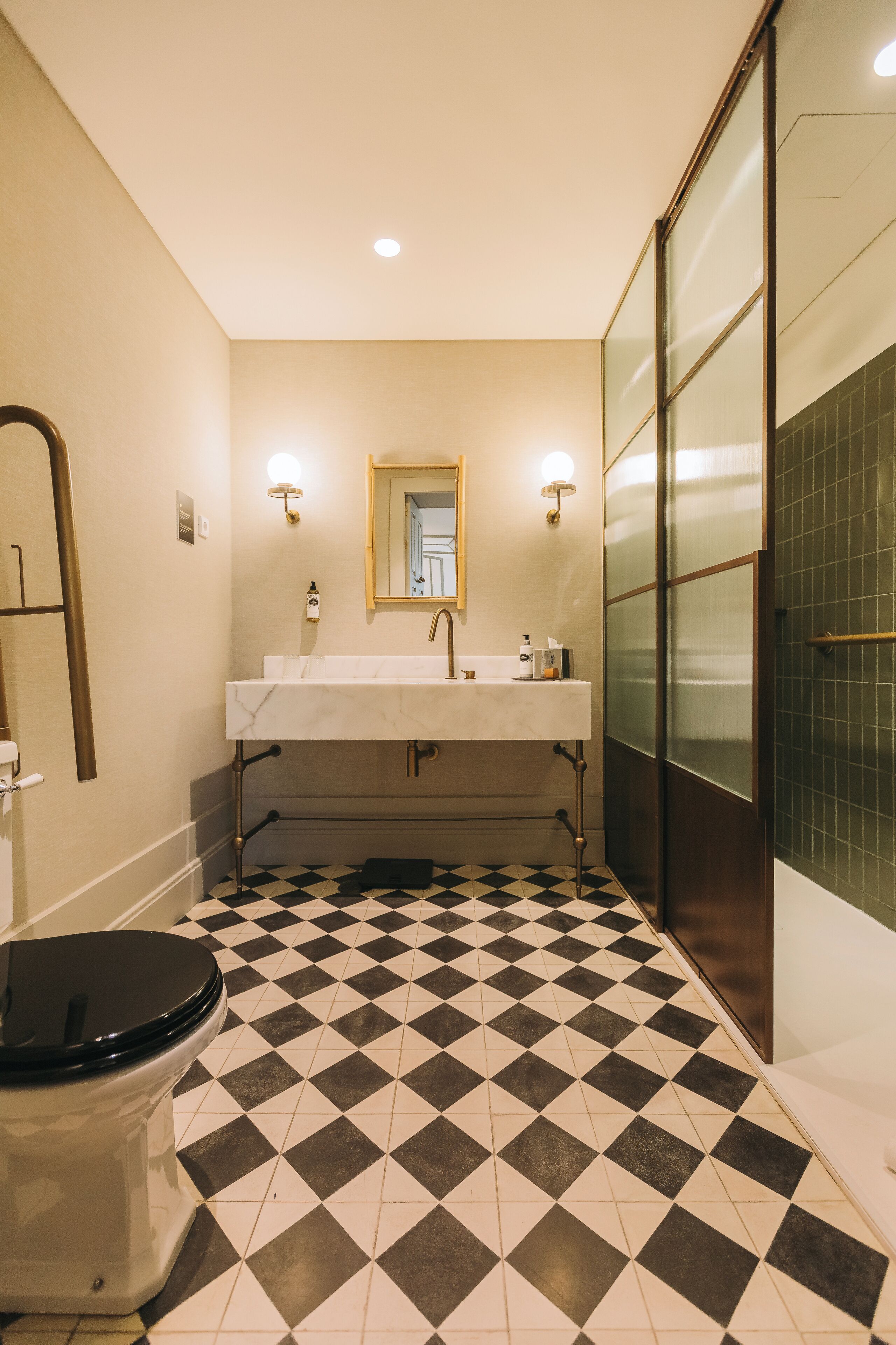A bathroom with a checkered floor, a white sink, a mirror, and a toilet.