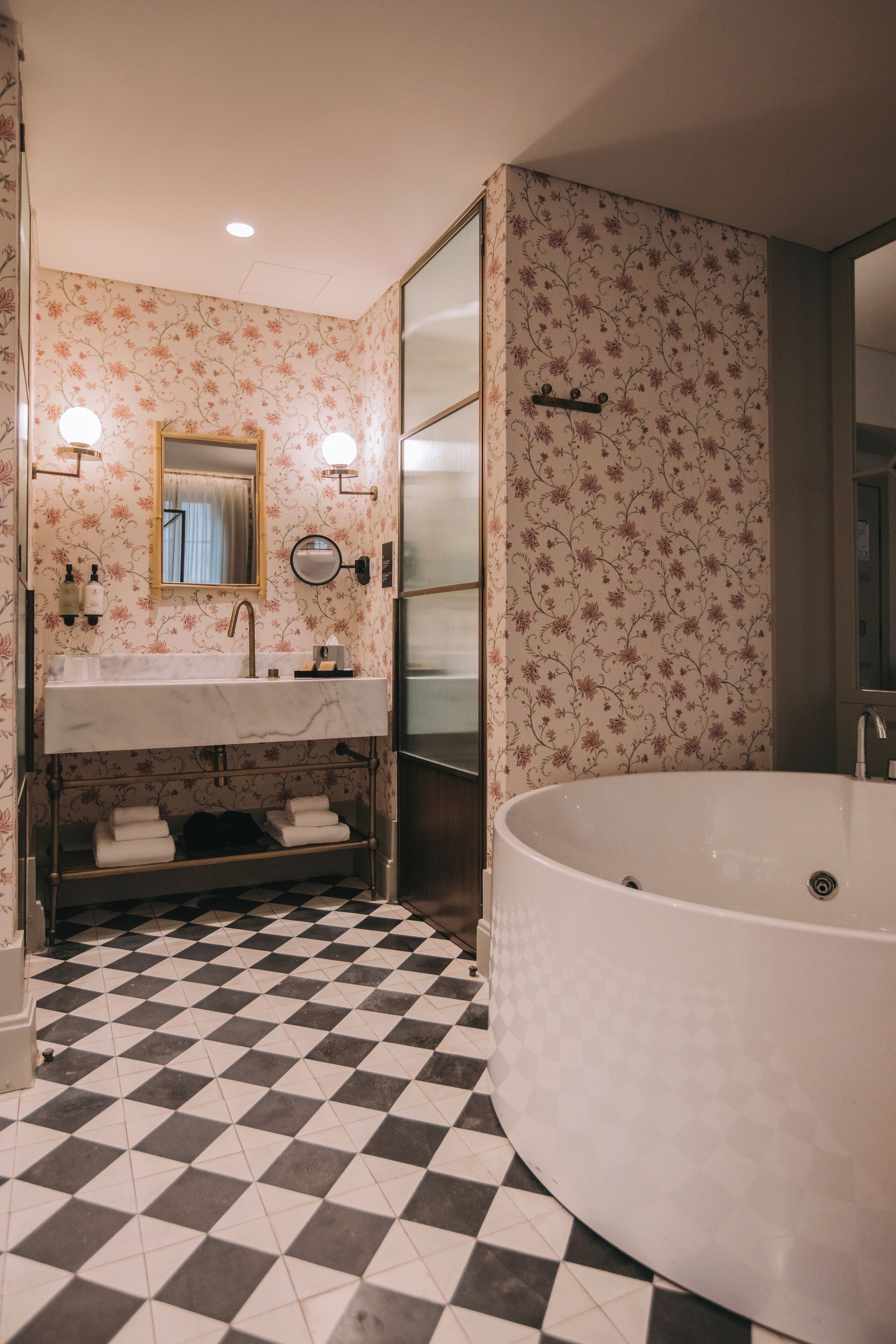 A bathroom with a checkered floor, a sink with a mirror, and a freestanding bathtub.