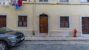 A building with a cobblestone street, a parked car, and a red fire hydrant.