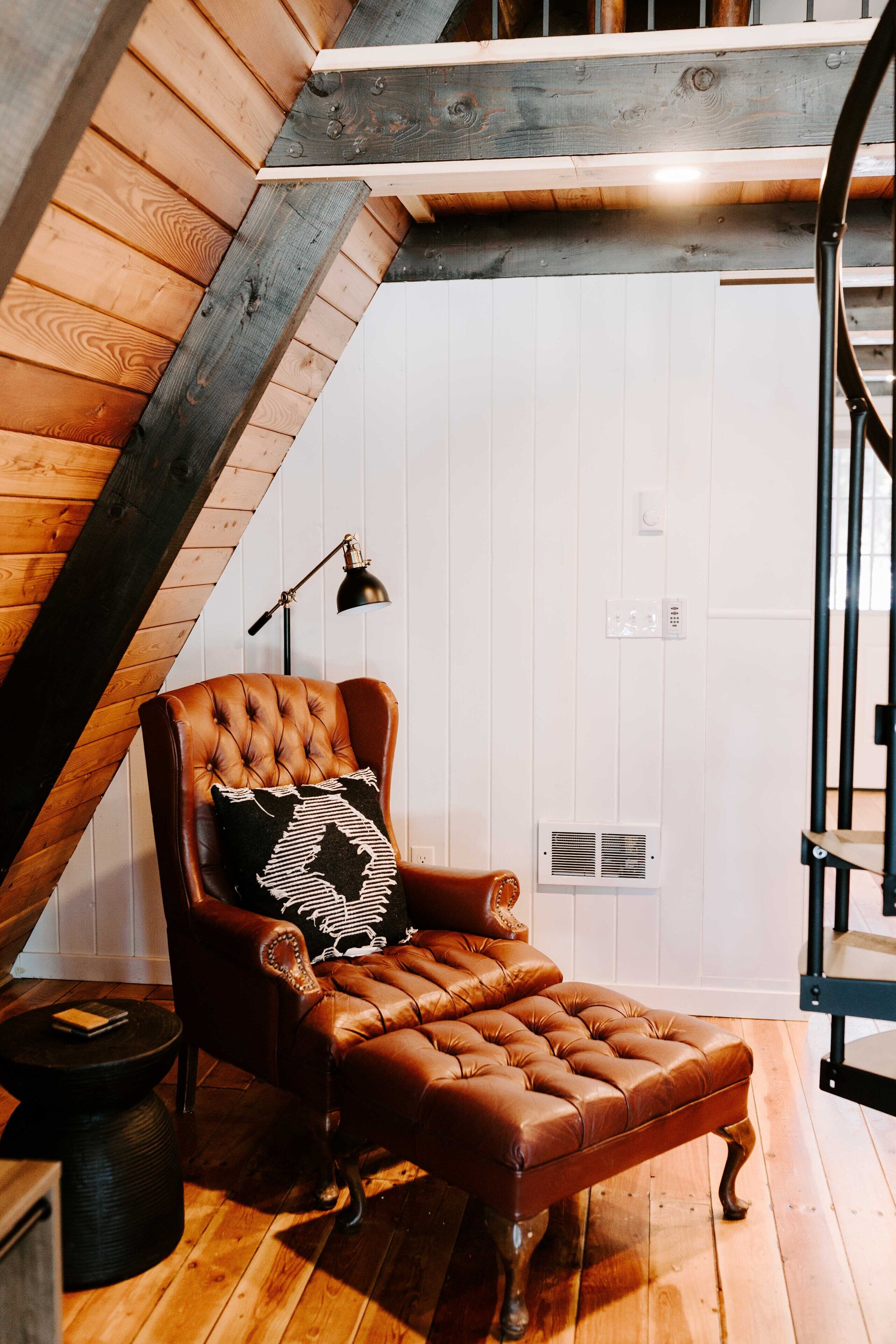 Une pièce chaleureuse avec un fauteuil en cuir, une petite table d’appoint et un plancher en bois.
