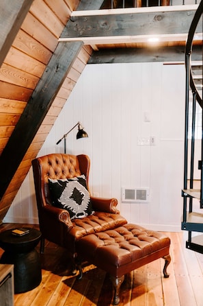 Une pièce chaleureuse avec un fauteuil en cuir, une petite table d’appoint et un plancher en bois.