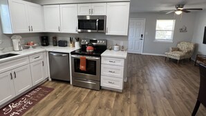 Una cocina moderna con armarios blancos, electrodomésticos de acero inoxidable y suelo de madera.