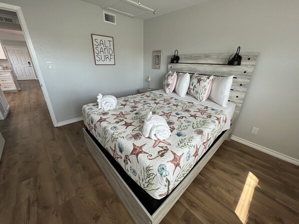 A bedroom with a bed, a headboard, a wall-mounted sign, and a hallway.