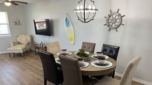 Un comedor con una mesa redonda, sillas y un televisor montado en la pared.
