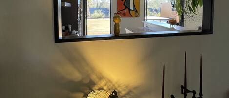 A modern interior with a large mirror, pendant lights, and decorative items on a white surface.
