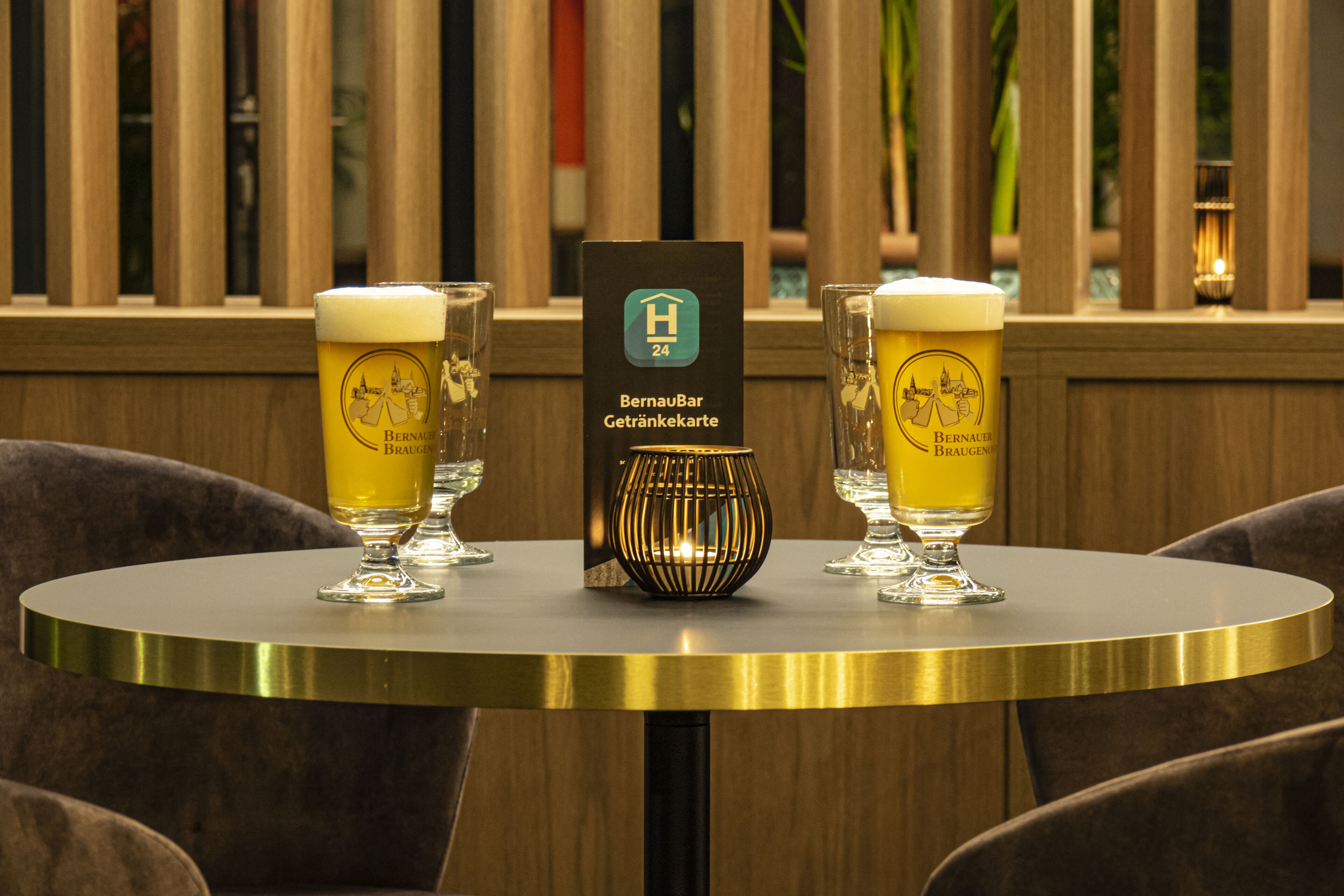 Una mesa redonda con dos vasos de cerveza y una carta.