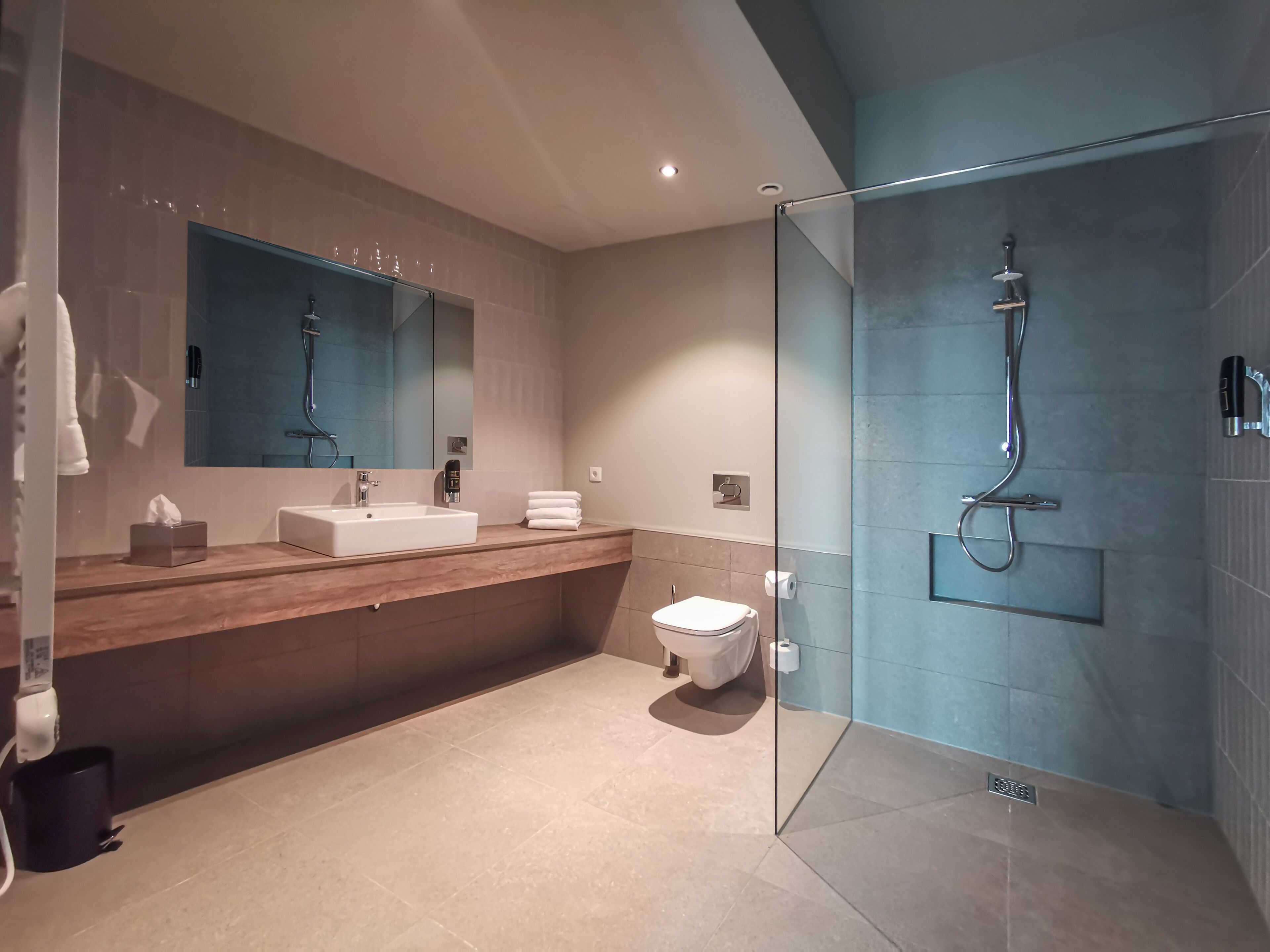 A modern bathroom with a glass-enclosed shower, a sink with a mirror, and a toilet.