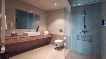 A modern bathroom with a glass-enclosed shower, a sink with a mirror, and a toilet.