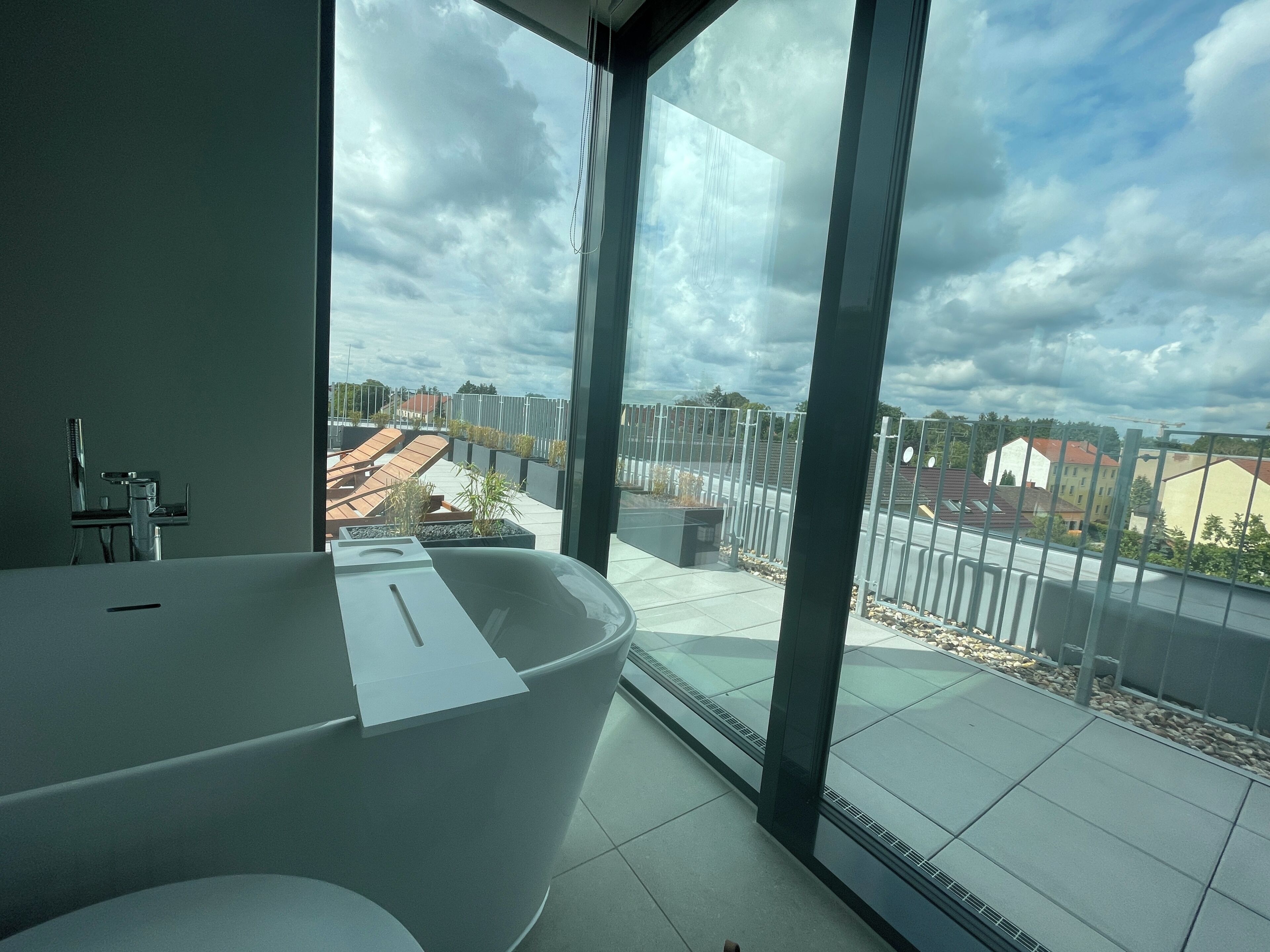 Ein modernes Badezimmer mit einer großen Badewanne, einer Toilette und einem Fenster mit Blick auf die Stadt.