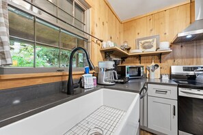 A modern kitchen with a large sink, a coffee maker, a microwave, and a stove. - Walk to town,covered deck dining,wood-burning fireplace (Highlands)