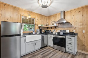 Una cucina moderna con elettrodomestici in acciaio inox, rivestimenti in legno e una finestra con vista sul verde.