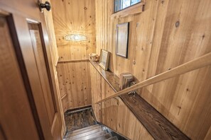 A wooden interior with a staircase, a wall-mounted light fixture, and a framed picture. - Walk to town,covered deck dining,wood-burning fireplace (Highlands)