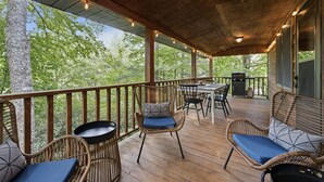 Une terrasse extérieure avec des meubles en osier, un barbecue et une vue sur les arbres.