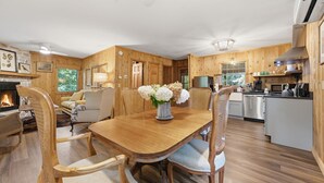 Un intérieur en bois comprenant une table à manger, des chaises, une cheminée et un coin cuisine.