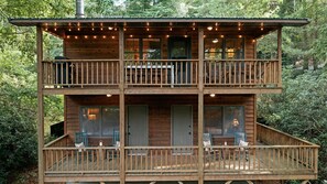 A two-story wooden cabin with a balcony, windows, and outdoor seating. - Walk to town,covered deck dining,wood-burning fireplace (Highlands)