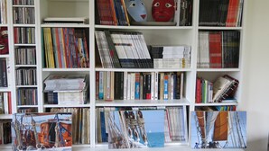 Una estantería llena de libros y DVD, algunos con títulos y autores visibles.