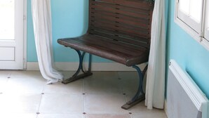 Una habitación con pared azul, un banco de madera, un reloj y un radiador.