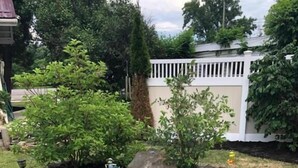 A garden bed with a variety of plants and a small tree, surrounded by a stone border. - Oakes Oramel Inn (Belfast)